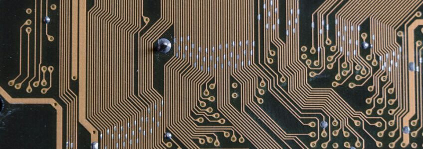 An almost black circuit board with bright gold wires and silver sauter